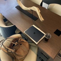 a conference room with a purse, drink and computer